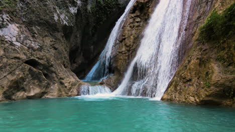 aerial view of pristine waterfall flowing down the rocky cliff in sumba island, indonesia