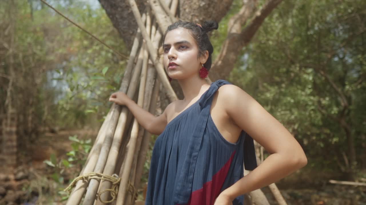 una fotografía de primer plano exquisitamente capturada de una mujer vestida con gracia posando en medio de un telón de fondo de árboles
