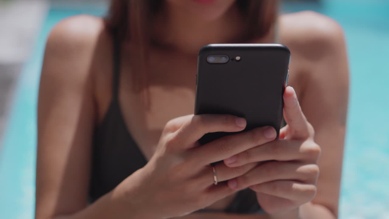 Donna che usa il telefono a bordo piscina
