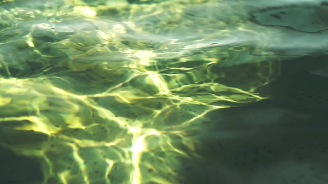 Slow-motion, close-up of water surface ripples projected on a swimming pool's bottom.