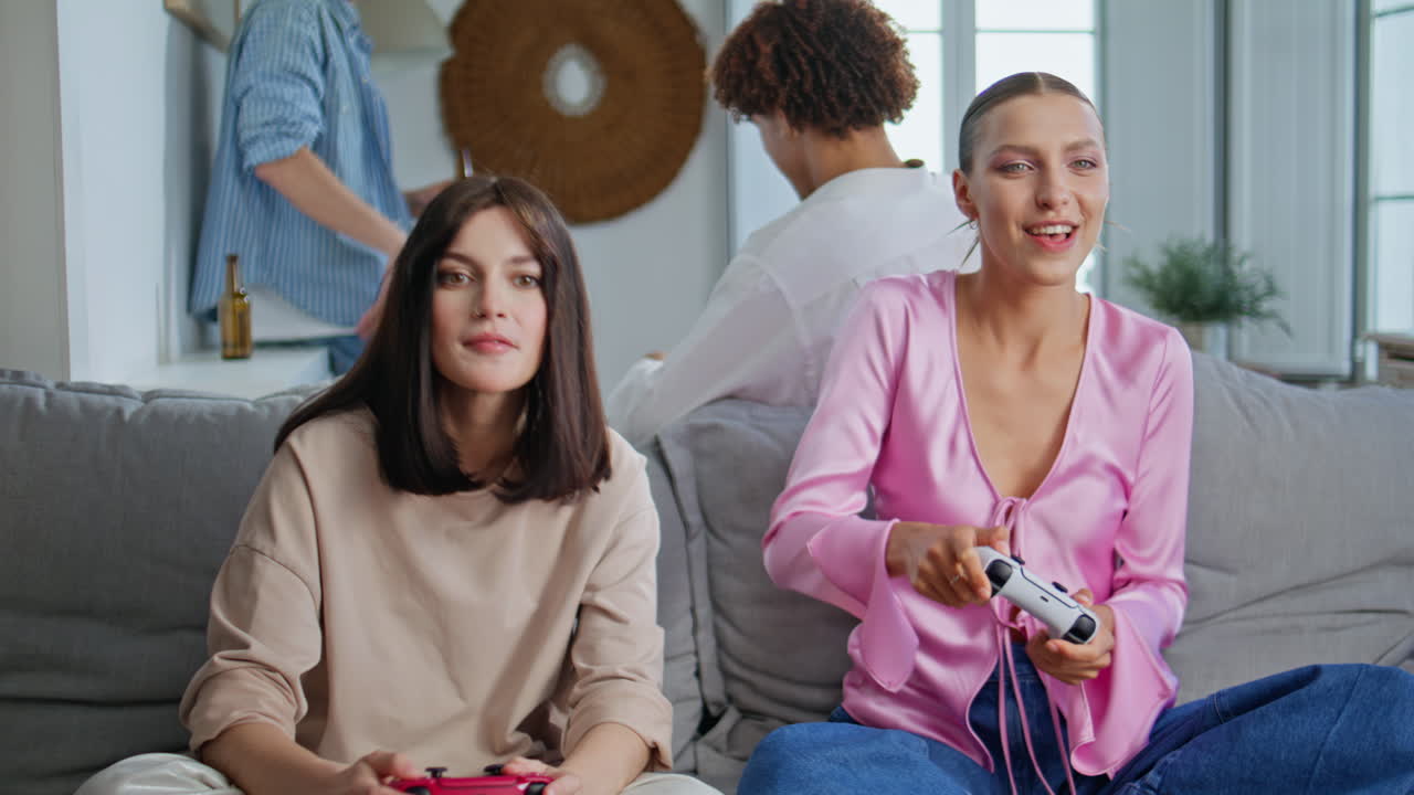 Excited gamers rejoicing video game at home closeup. Girls holding consoles