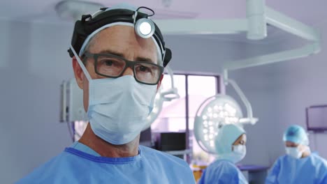 primer plano de un médico caucásico de pie en un faro quirúrgico en la sala de operaciones de un hospital