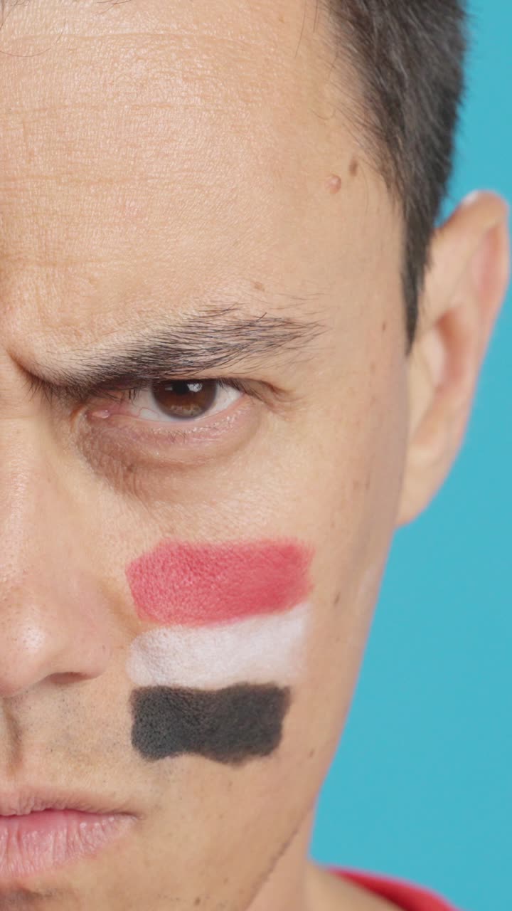 Serious man with a egyptian flag painted on the face