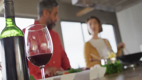 pareja feliz diversa cocinando juntos, mezclando ingredientes en sartén en la cocina