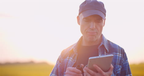 agricultor examinando el campo agrícola mientras trabaja en una tableta digital en la granja 20