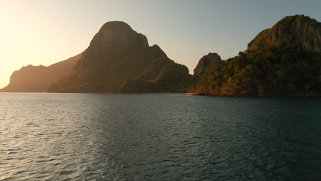 Vuelo-Aéreo-A-Baja-Altura-Sobre-El-Agua-Que-Muestra-La-Isla-Cadlao-Con-Puesta-De-Sol-Y-Hora-Dorada-En-El-Nido,-Palawan,-Filipinas