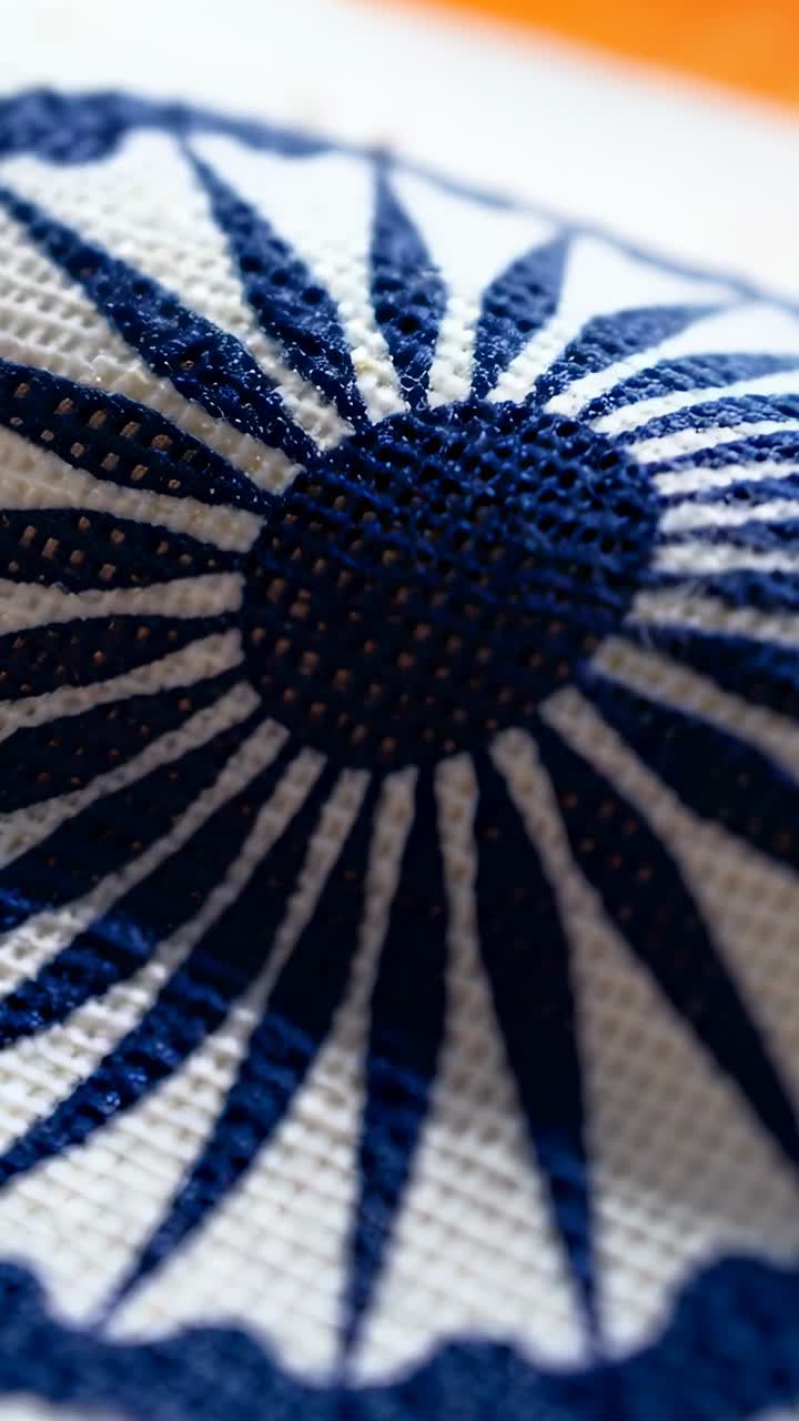 Vertical video: Tilting lens panning blue wheel on white linen, showing orange stripe, stitch