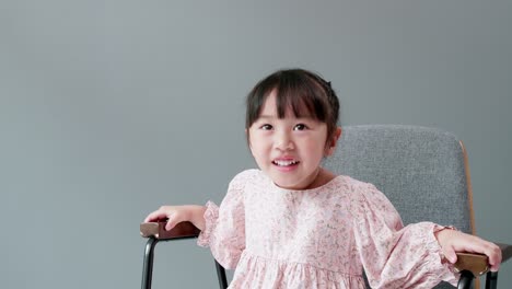 Cheerful-and-happy-Asian-children-3-Years-old-Sitting-in-a-chair-in-front-of-the-gray-background