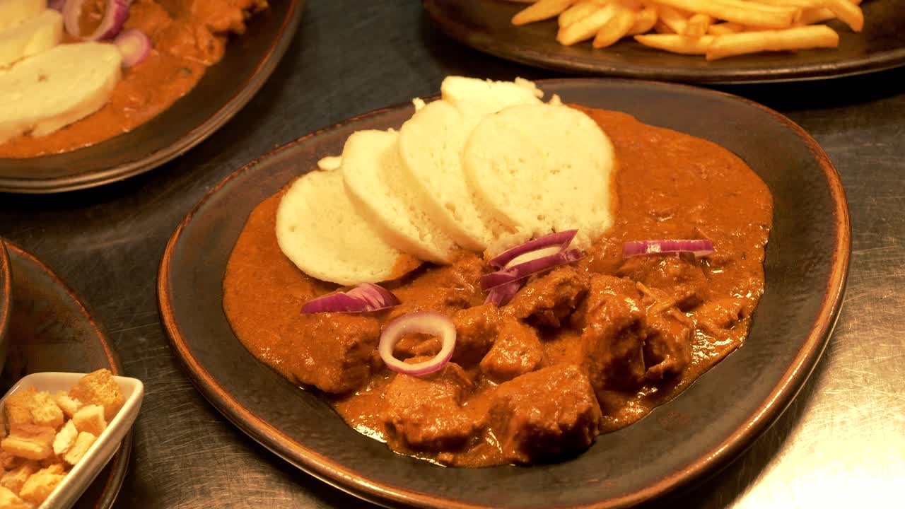 platos en la mesa, goulash con pan y anillos de cebolla roja