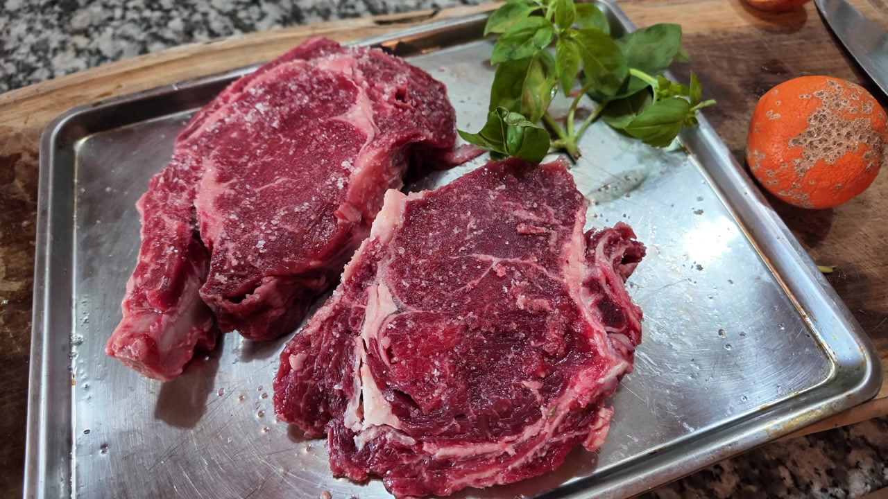 Nærbilde av krydrede rå ribeye biffsteker klare for grill på kjøkkenbord