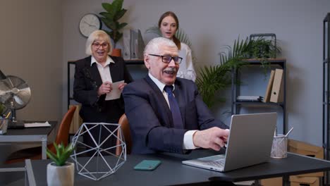 Senior-professional-businessman-grandfather-company-director-celebrating-victory-in-office-interior