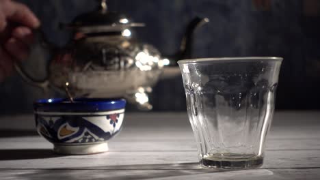 cinemagraph of closeup of tea pouring into a glass with moroccan tea set and mint