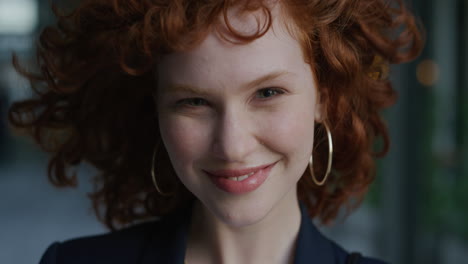 close up portrait young beautiful business woman smiling looking at camera wind blowing hair cute red head female feminine beauty slow motion wearing earings