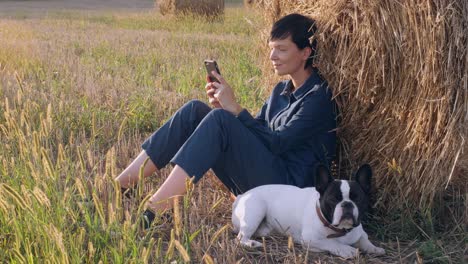 girl with dog resting messaging on smartphone outdoors.