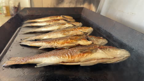 healthy fsh cooked on the grill with appetizing steam. sea bream and sea bass. slow motion. close up, side shot, daytime 4k