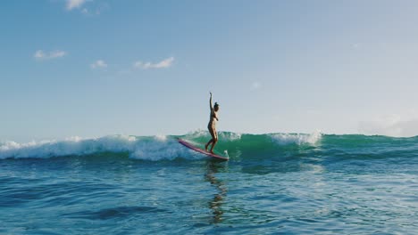 young woman surfing at sunset