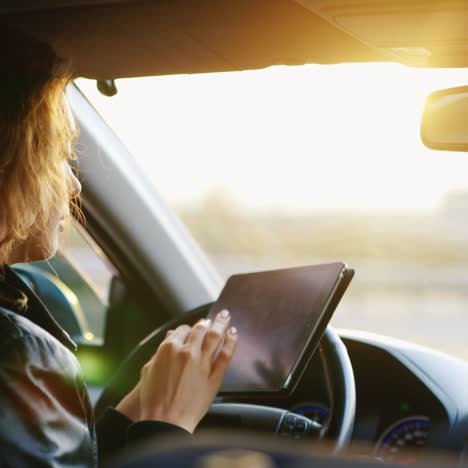 a young woman uses a tablet in the car navigating and orienting in an unfamiliar place