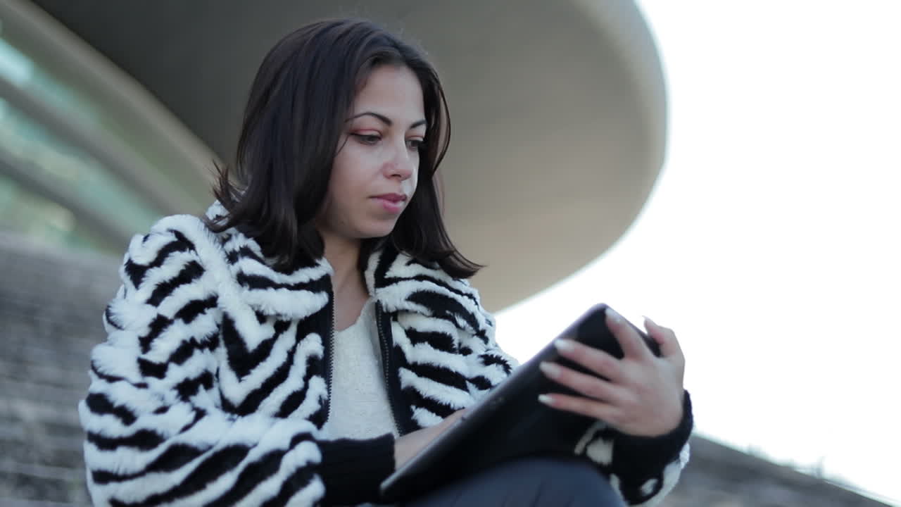 mujer joven enfocada usando la tableta al aire libre