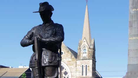 estatua de bronce de un soldado de día con la catedral en el fondo