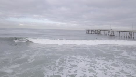 surfer catches a wave at venice pier in the morning