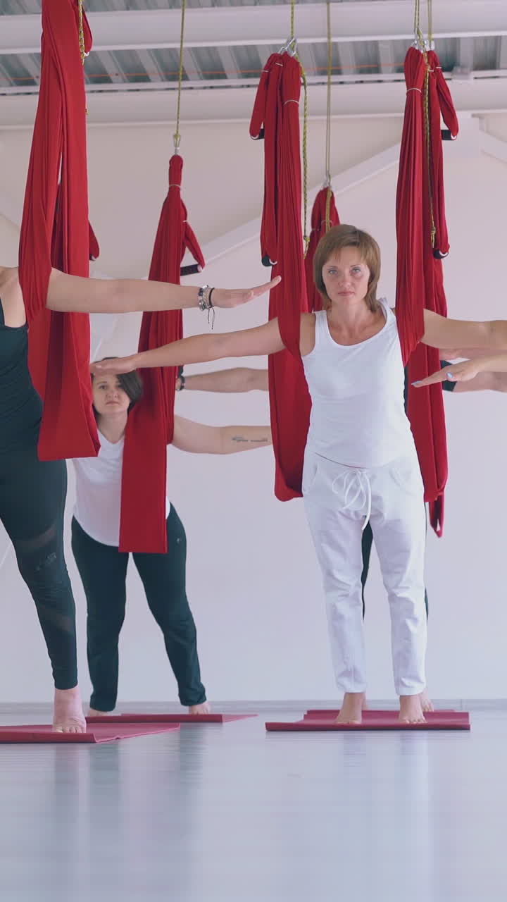 pretty young ladies practice pilates with hammock and show mountain yoga asana in gym renovated relaxation zone