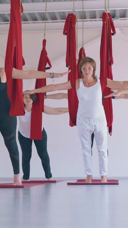pretty young ladies practice pilates with hammock and show mountain yoga asana in gym renovated relaxation zone
