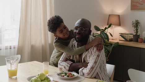 padre e hijo abrazados junto a la mesa del comedor