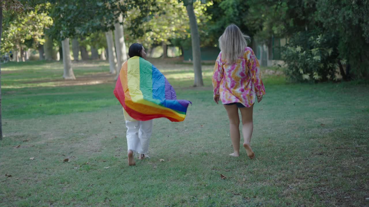 Two Women Walking in a Park with a Rainbow Flag