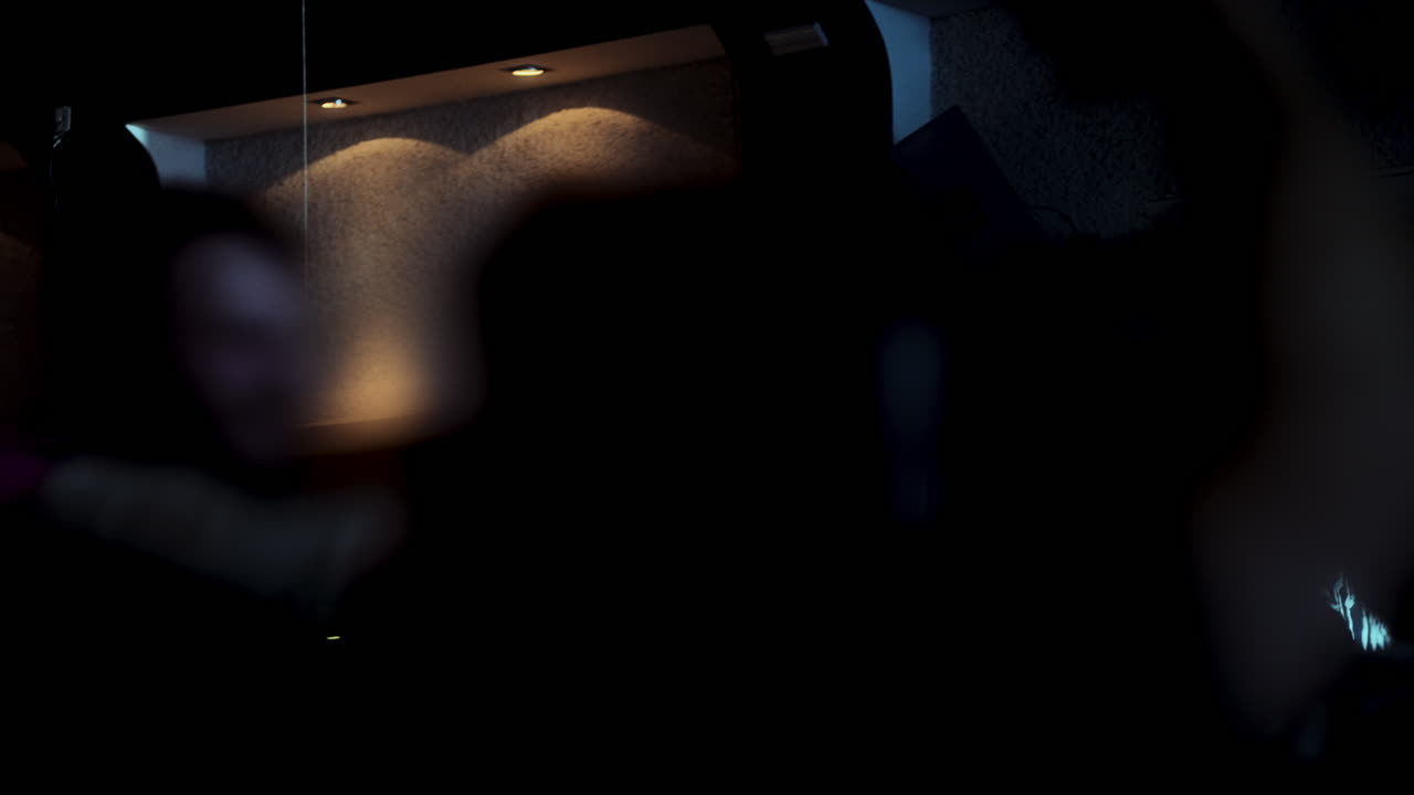 Blurred silhouettes moving rhythmically across dimly lit nightclub dance floor, capturing energetic nightlife with anonymous dancers creating vibrant, pulsing atmosphere of youth and joy