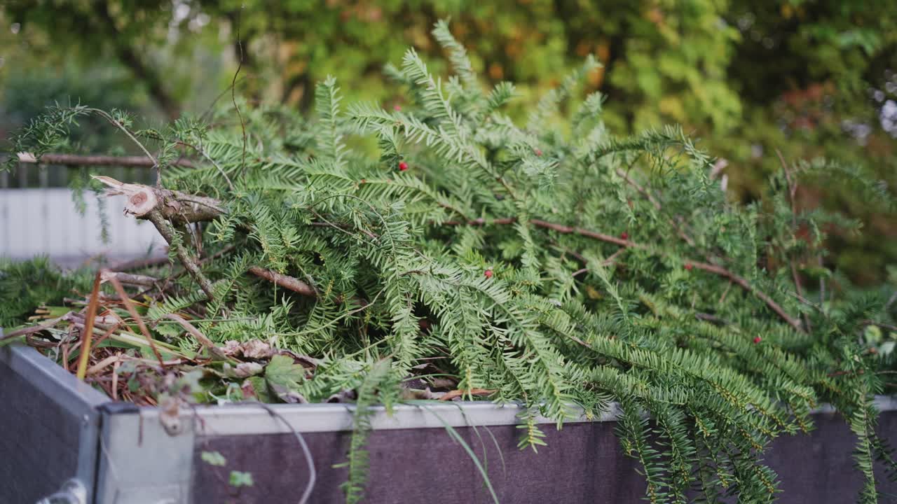Close-up of a trailer corner in a traditional German garden, showing tree and shrub cuttings, textures of wood and metal, and seasonal garden work details
