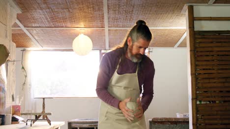 Male-potter-putting-clay-pottery-wheel-in-pottery-workshop