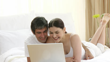 mujer y hombre en la cama usando una computadora portátil