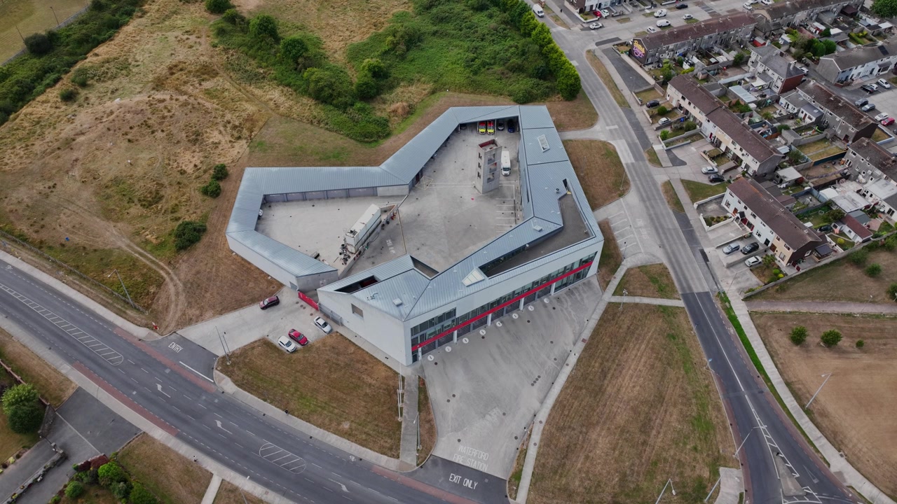 Vista aérea en picado de la Estación de Bomberos de la Ciudad de Waterford, Irlanda, capturando el complejo de la estación de bomberos, las vías de acceso, las propiedades vecinas y el paisaje urbano más amplio.