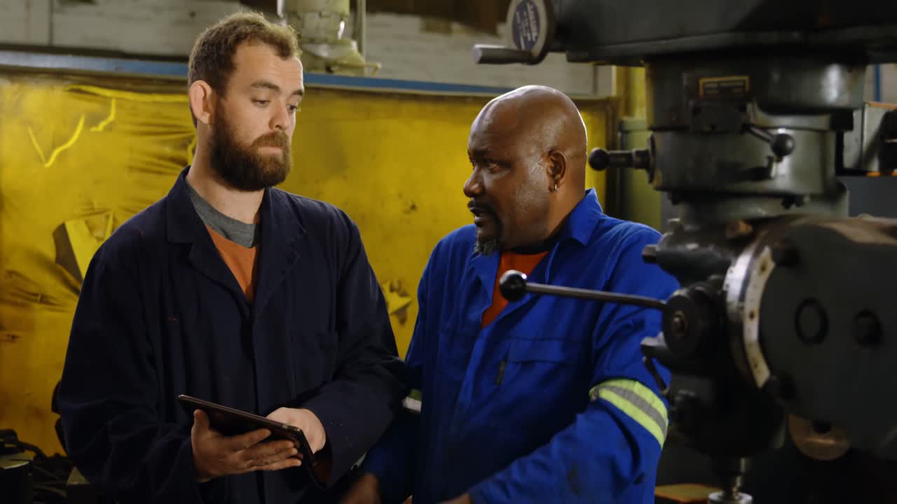 Two metalsmiths discussing over machine 4k