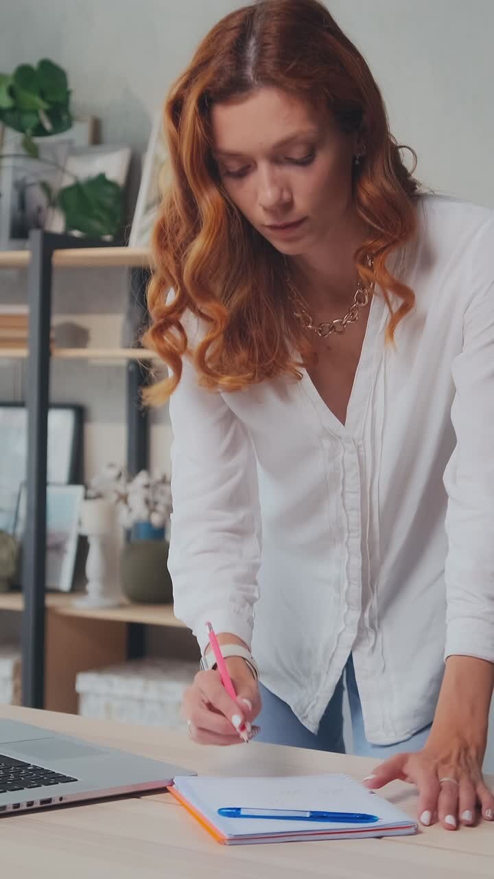 Young focused caucasian woman accountant using laptop stands in home office