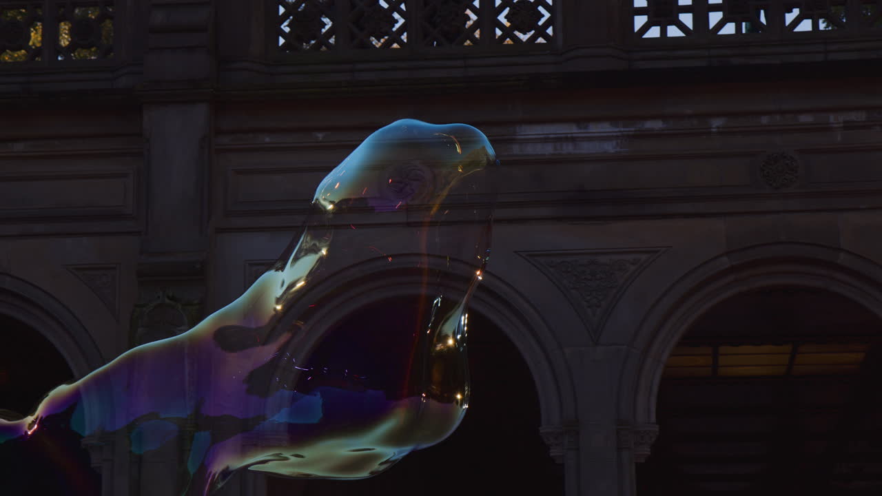 건물 옆 공기에 떠 있는 비누 거품 모양, 바람에 의해 확장 및 이동, 연약한 빛의 화려한 투명 모양 비행