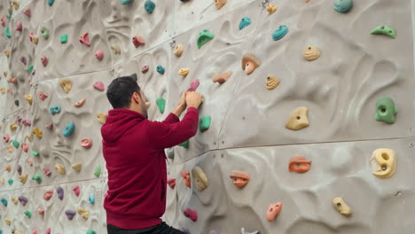 un hombre escalador sube a una pared de escalada sin seguro en un campo deportivo al aire libre
