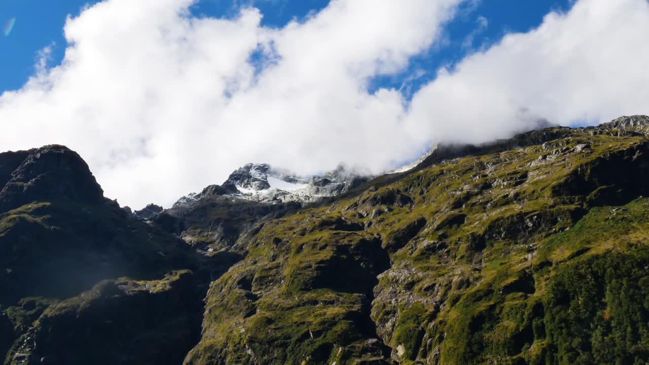 lapso de tiempo de abajo hacia arriba del espectacular paisaje nuboso que cubre las cumbres de las montañas nevadas durante el día de verano