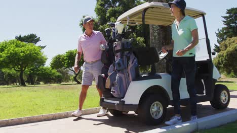 pareja de mayores caucásicos quitando palos de golf de la parte trasera de un carrito de golf en el campo de golf