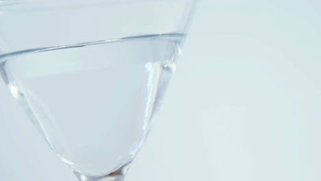 Grey-paper-burning-over-close-up-of-cocktail-glass-against-grey-background