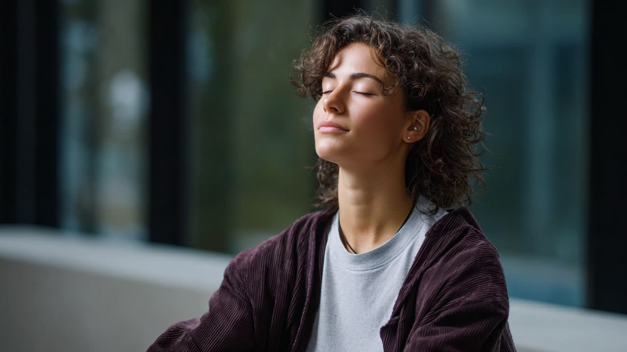 Una mujer joven en un entorno acogedor experimenta tranquilidad y encarna la atención plena y la paz interior mientras se toma un momento para la autorreflexión y la relajación.