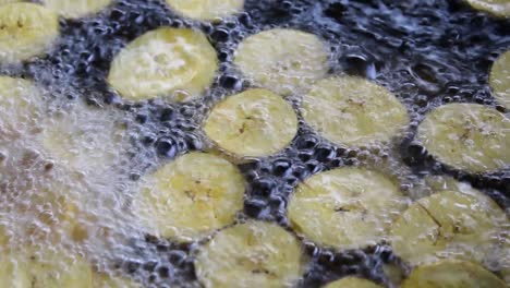 cooking fried plantains, fried plantains floating in boiling oil, close shot to fried plantains, banana chips in boiling oil