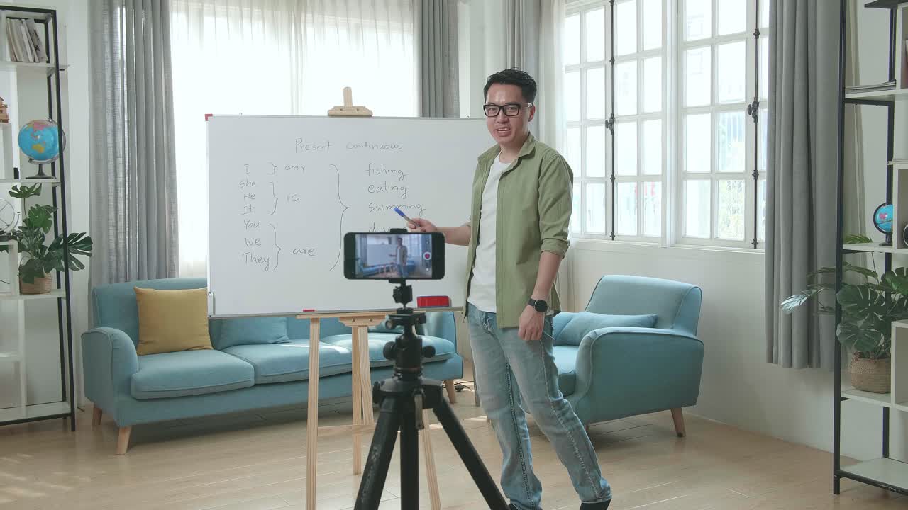Asian Male Teacher With Glasses Shoots Video By Smartphone Camera While Teaching English At Home