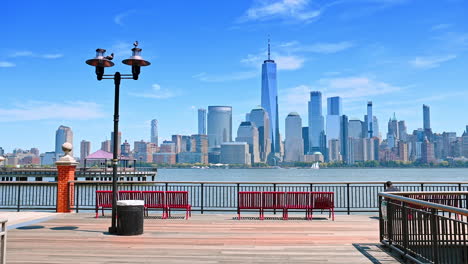 a walk by the beautiful pier with lanterns and red benches in sunny jersey. spectacular scenery of manhattan over the hudson