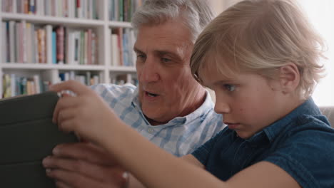 abuelo mostrando a un niño pequeño cómo usar una computadora tablet enseñando a un nieto curioso tecnología moderna niño inteligente aprendiendo dispositivo móvil sentado con el abuelo en el sofá 4k