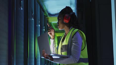 African-american-female-computer-technician-using-laptop-working-in-business-server-room