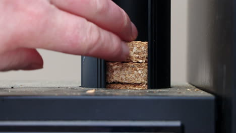 Stack-Of-Hardwood-Bisquettes-Dropping-Inside-A-Wood-Puck-Smoker