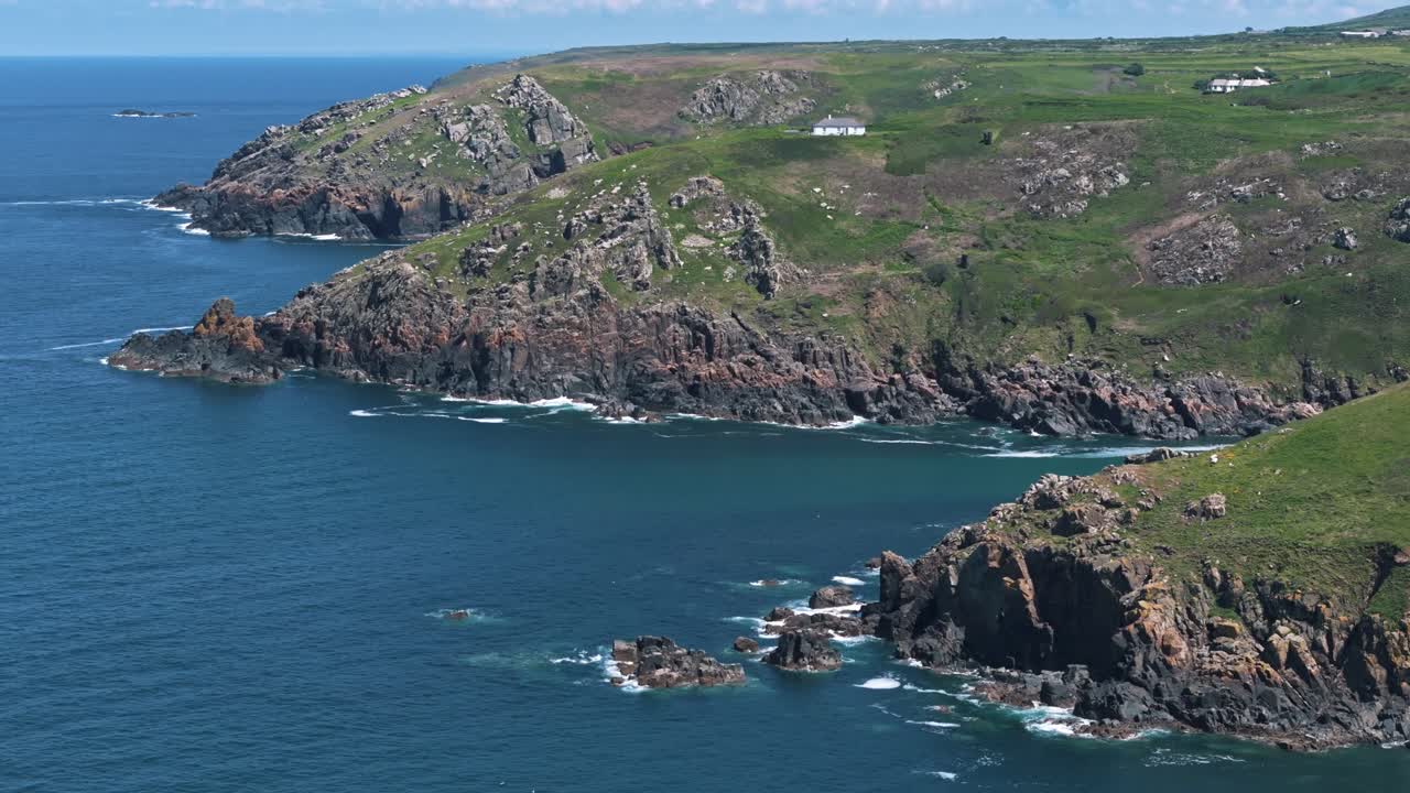 Slow aerial circle left over rugged coastline with turquoise sea and dramatic rock features