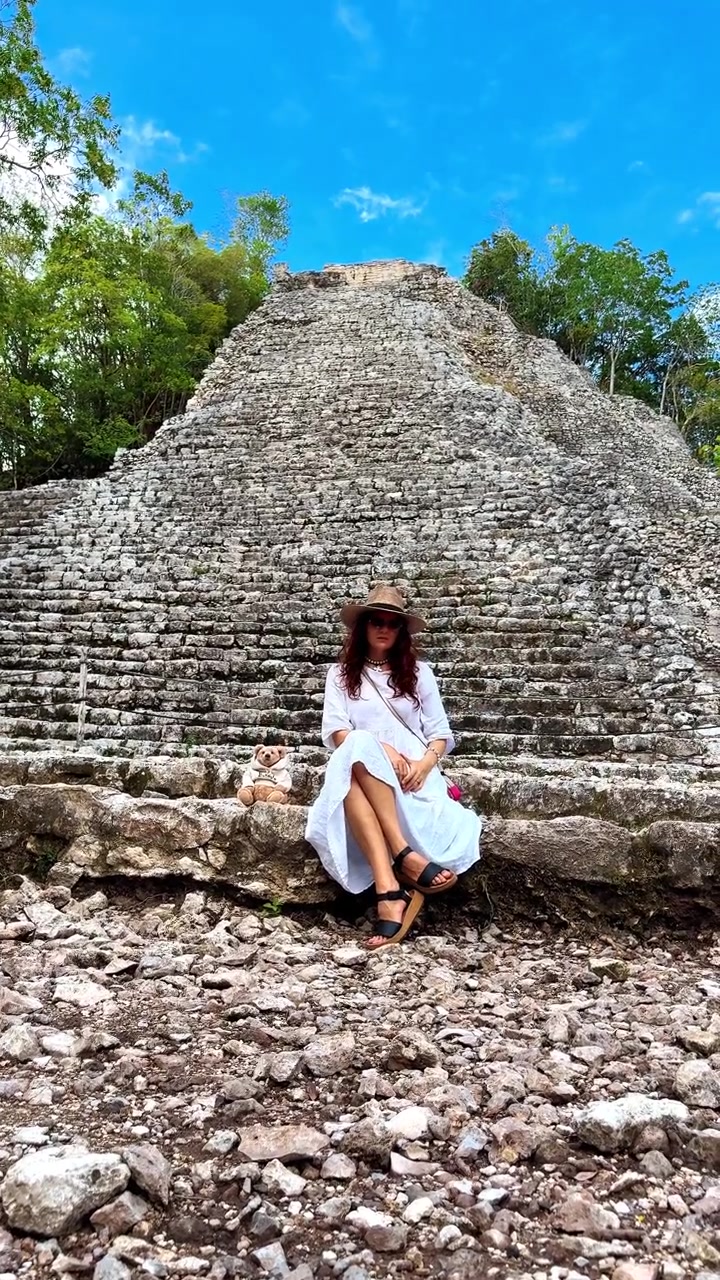 Una persona si siede vicino ad antiche rovine in Messico durante una giornata di sole. Una donna si gode il suo tempo nel sito archeologico in Messico.