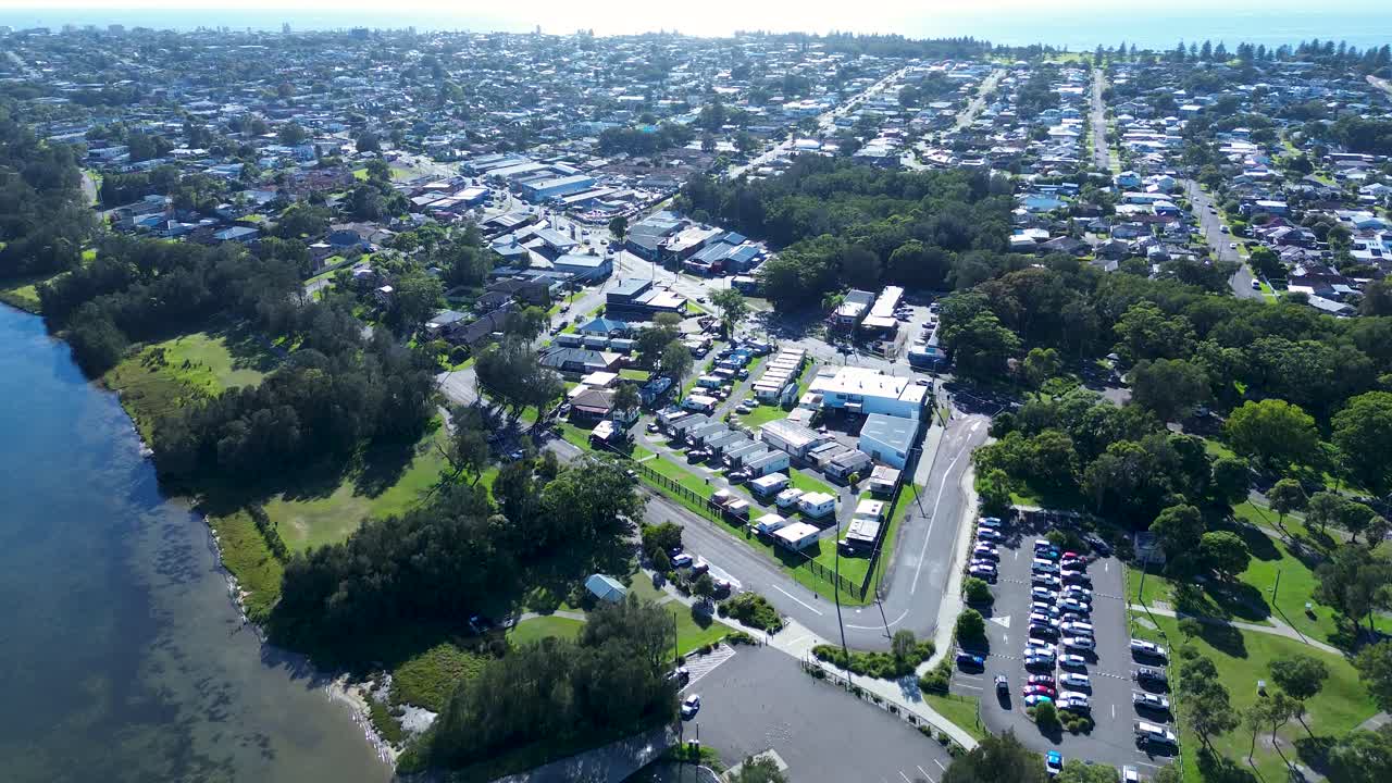 Drone aerial landscape of Long Jetty suburban rural town neighbourhood with main road carpark shops by Tuggerah lake lagoon Central Coast Australia urban tourism infrastructure outdoors community
